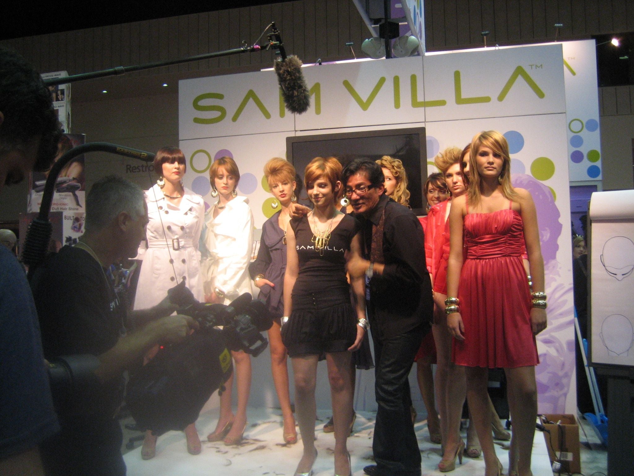 Sam Villa with models in front of TV camera covering Sam Villa launch