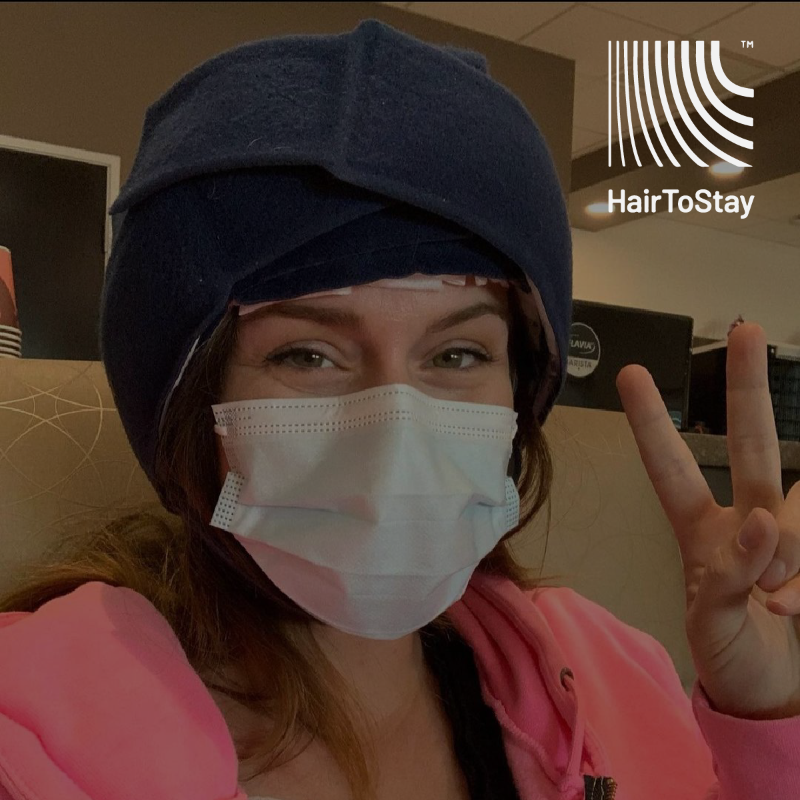 Woman in a medical mask with the "Hair to Stay" logo.