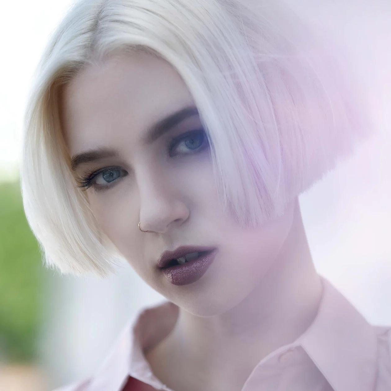 Platinum-white-blonde model with sultry makeup and a short bob over a bright white background.